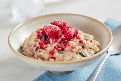 A bowl of porridge, topped with frozen raspberries